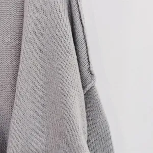 Close up view of grey knit cardigan fabric shoulder and collar detail, soft cozy texture.