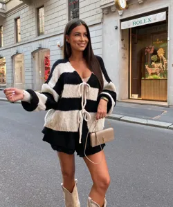 Detailed view of the stylish black and white striped cardigan worn in a chic urban street scene.