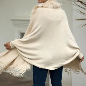 Women's beige knit batwing sleeve poncho cape with faux fur collar and fringe hem detail.