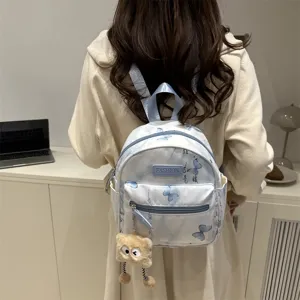 Detailed view of trendy butterfly printed mini backpack with cute plush charm in casual setting.