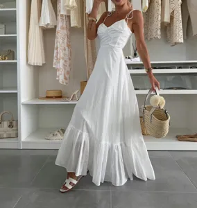White slip maxi dress with backless design and tiered hem for elegant vacation look.