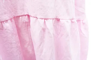 Pink tiered ruffle dress detail shot showing soft textured fabric and pleat craftsmanship.