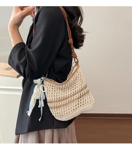 Handmade woven shoulder bag for women, stylish hollow bucket bag with chic ribbon and pearls.