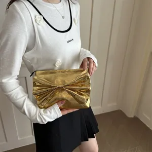 Stylish metallic gold clutch bag with large bow design for women evening party use.