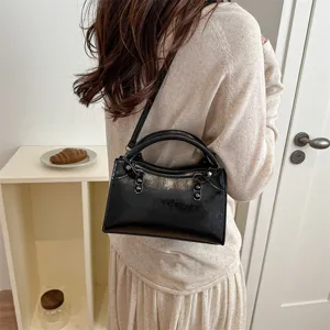 Detail shot of Korean style minimalist black glossy shoulder and crossbody bag with handle.