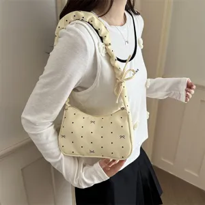 Detail shot of a sweet yellow polka dot crescent shoulder bag with cute bow and pleated strap.
