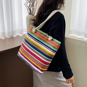 Colorful striped canvas shoulder bag detail view with thick rope handle in indoor scene.