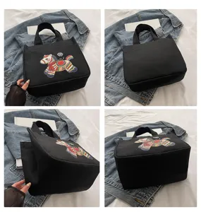Detailansicht der schwarzen Canvas-Handtasche mit traditionellem chinesischen Stickpferd.
