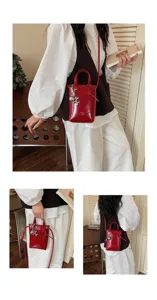 Petit sac bandoulière rouge en cuir avec charm en métal et bandoulière élégante pour femmes.