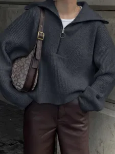 Detailopname van een donkergrijze geribbelde gebreide trui met halve rits en comfortabele pasvorm.