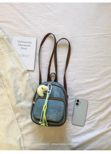 Vue détaillée du mini sac à dos en denim élégant avec des bretelles marron et un joli pendentif.