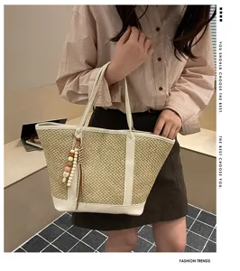 Stylish summer straw woven tote bag for women with chic leather trim and cute bead pendant.