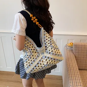 Detailweergave van een blauw-witte gehaakte tote tas met houten kralen handriem.