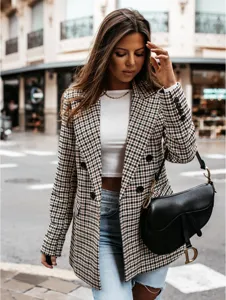 Detail shot of a stylish houndstooth blazer jacket worn by a model in an urban street setting.