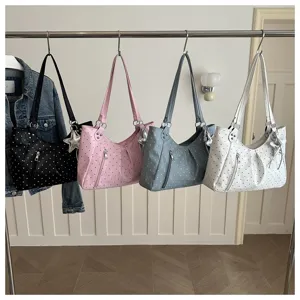Detailed view of fashionable polka dot shoulder tote bags in multiple colors hanging on rack.