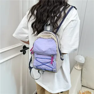 Detail view of stylish mini backpack with bungee cord design and vibrant purple accents.