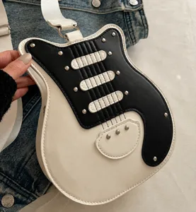 Guitar shape shoulder bag detail showing black and white color block and metal rivet accents.