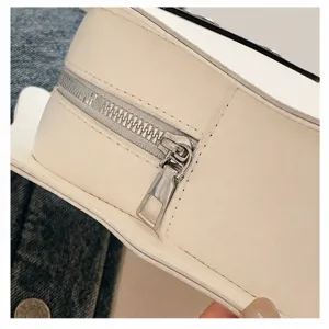 White crossbody bag metal zipper detail showing smooth pull and premium leather texture.