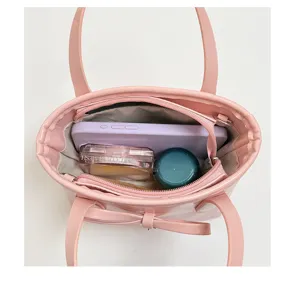 Dettaglio borsa secchiello rosa con fiocco che mostra interno spazioso e scomparti essenziali.