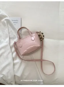 Dettaglio di mini borsa a tracolla in pelle verniciata rosa con finitura lucida e tracolla.