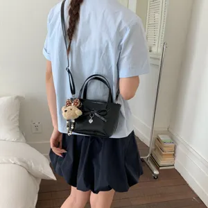 Elegante borsa a secchiello nera con fiocco e ciondolo orsetto, borsa a tracolla versatile.