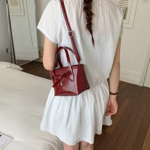 Squisita borsa a secchiello in vernice rosso vino con grazioso fiocco e ciondolo cuore.