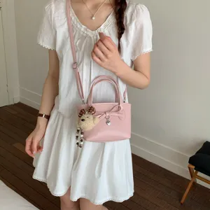 Borsa a secchiello rosa alla moda da donna con grazioso fiocco e ciondolo orsetto.