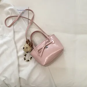 Elegante borsa a secchiello in pelle verniciata rosa con fiocco e ciondolo orsetto peluche.