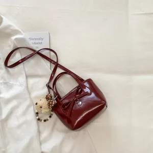 Chic borsa a secchiello rosso scuro con fiocco, ciondolo a cuore e ciondolo orsetto per donne.