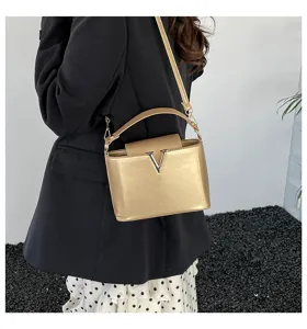 Sac à bandoulière doré métallisé élégant pour femme avec fermoir en métal en forme de lettre V.