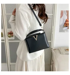 Vue détaillée du sac à main en cuir noir élégant avec fermoir doré en forme de V.