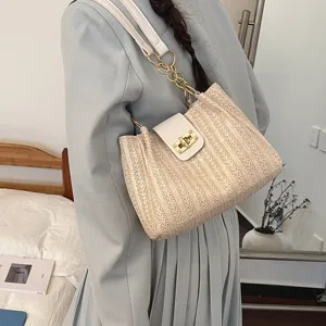 Détail du sac porté épaule tressé avec rabat blanc élégant et fermoir tournant doré chic.