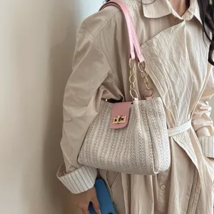 Détail de sac bandoulière tissé, lanière en cuir rose, chaîne en métal, fermoir élégant.