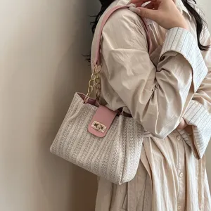 Vue détaillée du sac porté épaule tissé avec rabat rose et fermoir tournant pour femmes.