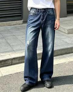 Close-up detail of distressed vintage straight leg denim jeans in dark blue wash style.