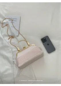 Vue détaillée du sac à main kiss-lock rayé rose et blanc avec bandoulière chaîne dorée élégante.