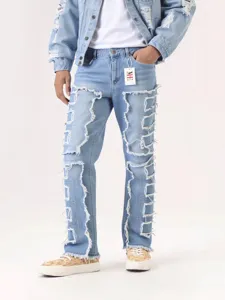 Gros plan sur le jean patchwork déchiré présentant des bords effilochés et un délavage clair.