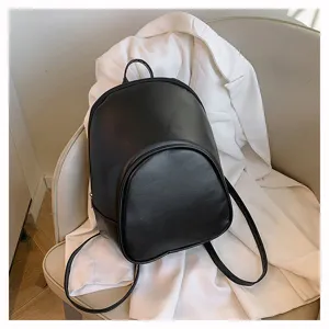 Close-up detail view of a minimalist black leather backpack displayed on a chair.