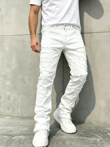 Detail shot of men's white distressed stacked denim jeans, showcasing heavy patchwork and fit.