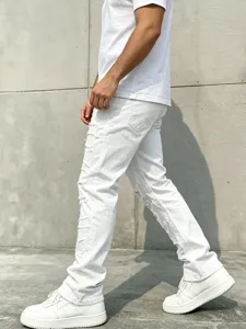 Close-up detail of mens white distressed flared jeans, showcasing ripped raw hem and slim fit style.