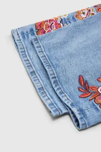 Primer plano detallado de unos jeans azul claro con un hermoso bordado floral colorido.
