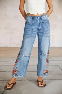 Detalles en primer plano de vaqueros azules anchos para mujer con hermosos bordados florales.