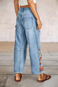 Vista detallada de vaqueros anchos para mujer en denim azul claro lavado con bordado floral elegante.