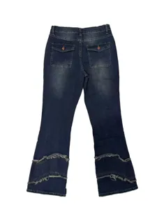 Close-up detail of women's dark blue micro-flared jeans featuring layered raw-edge hem.
