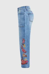 Vaqueros de mezclilla azul claro para mujer con bordado floral colorido en la pierna.