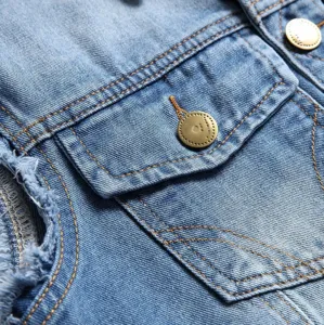 Detail shot of men's blue denim vest pocket, metal buttons, and frayed armhole craft.