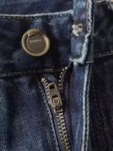 Primo piano dettagliato di jeans da uomo in denim blu scuro con cerniera metallica resistente.