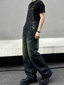 Detailed view of trendy loose-fit dark distressed denim bib overalls for men and women.
