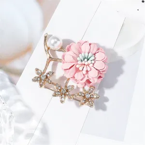 Gros plan d'une délicate broche fleur en tissu rose avec des perles et des strass étincelants.