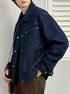 Vista dettaglio giacca jeans blu scuro uomo, vestibilità ampia stile workwear vintage.